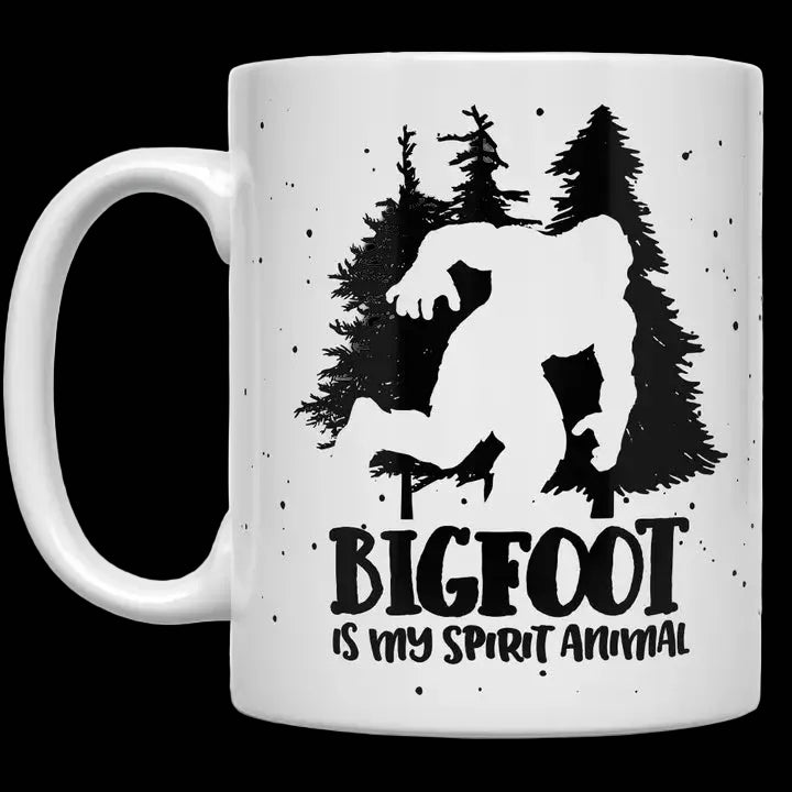 White mug with a black silhouette of Bigfoot and trees, and 'BIGFOOT is my spirit animal' text.