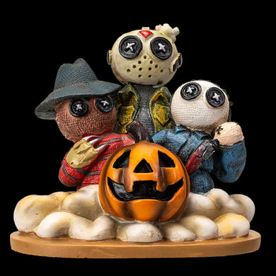 A set of three handcrafted dolls resembling characters from horror movies, seated on a cloud-like base, with one doll wearing a Freddy Krueger mask, another a Halloween mask, and the third a Texas Chainsaw Massacre outfit, all on a black background.