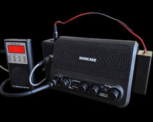 Black Sonicake electronic device with wires on a black background